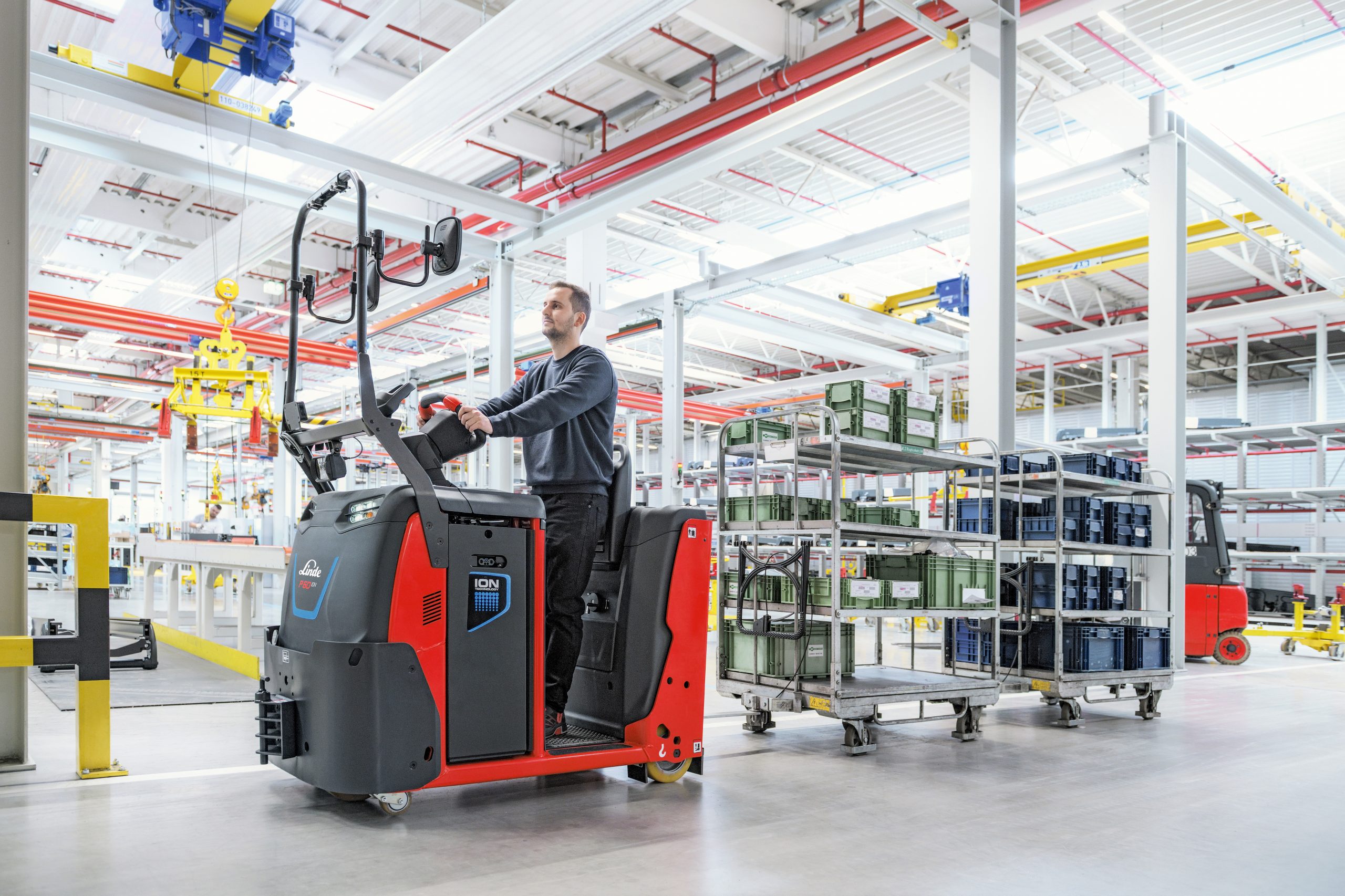 Employé utilisant un chariot Fenwick équipé de batteries ION pour transporter des bacs dans une usine moderne