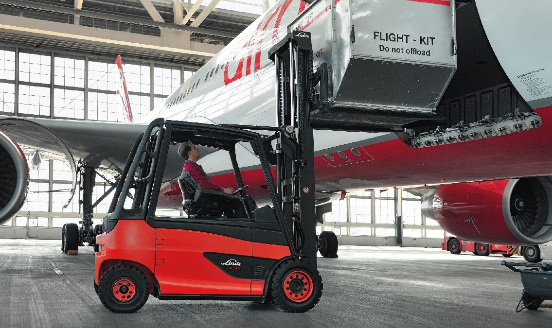 Chariot Fenwick transportant un flight kit sous un avion en maintenance dans un hangar